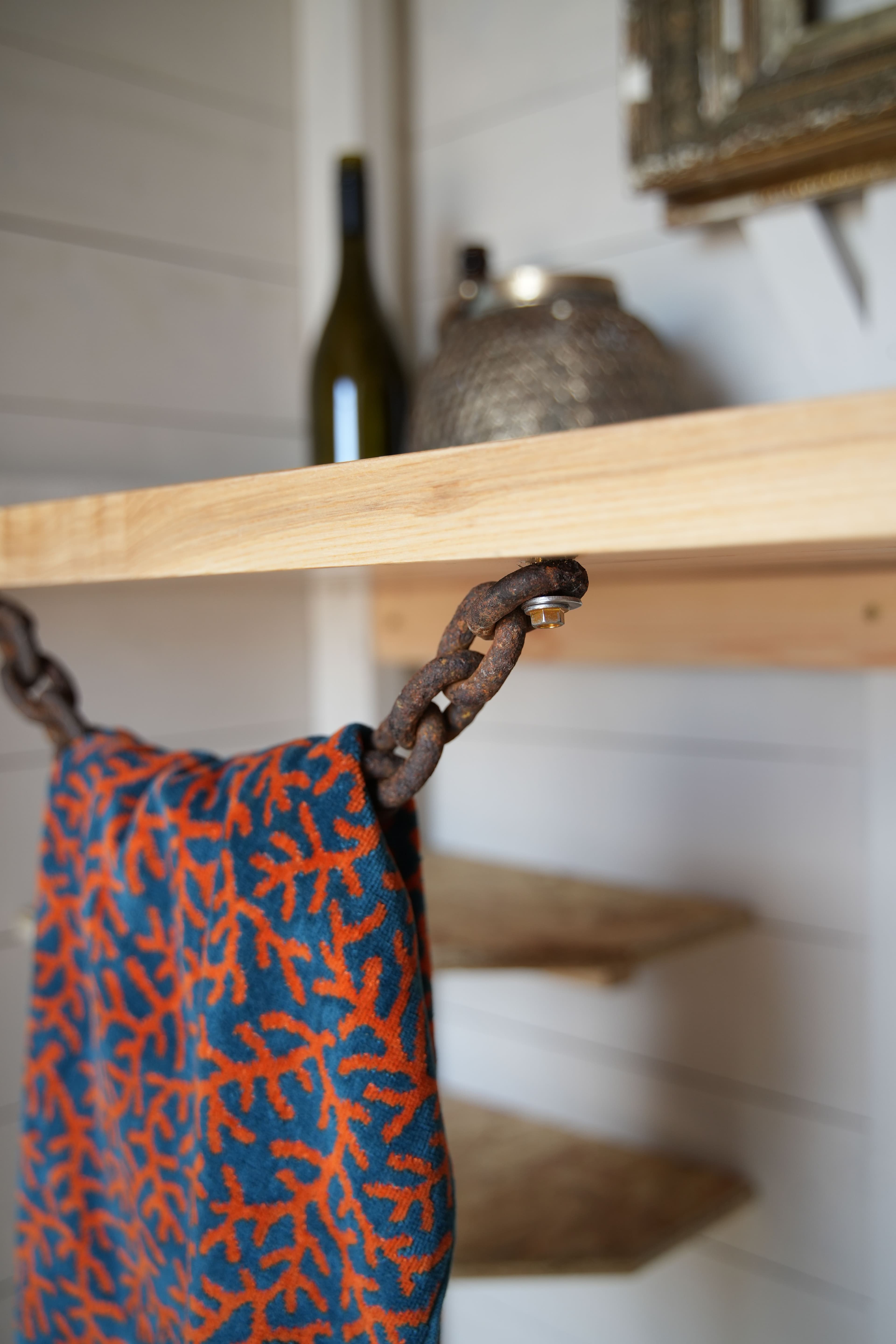 A close up of a towel rail made using a rusty chain found on the beach.