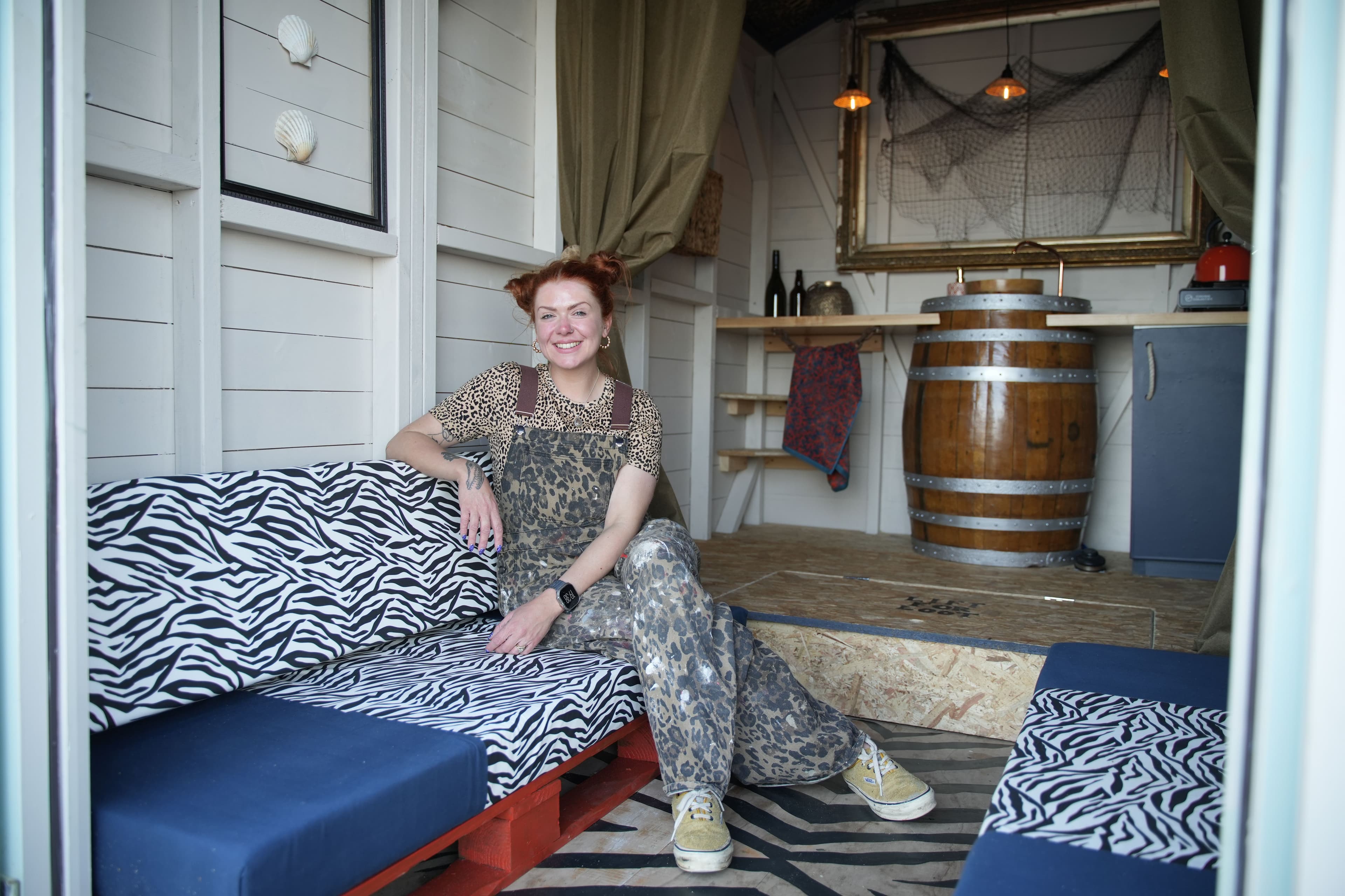 Designer Sophie sits proudly in her rock n roll beach hut complete with zebra print, a false floor and barrel sink.